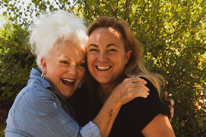 Bild von zwei Frauen, die fröhlich sind und sich umarmen.