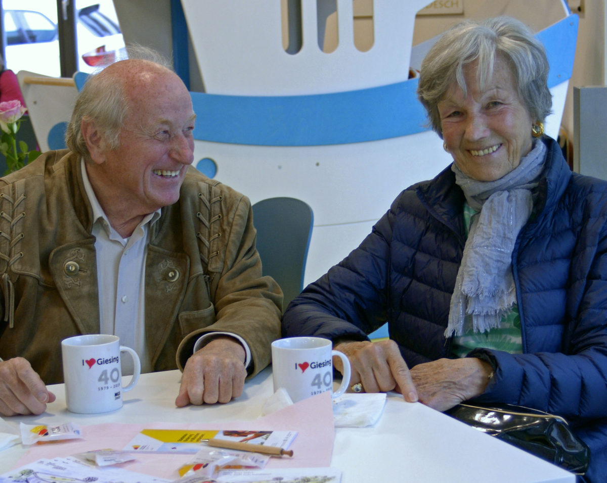 Zwei ältere Personen sitzen mit einer Kaffeetasse am Tisch.